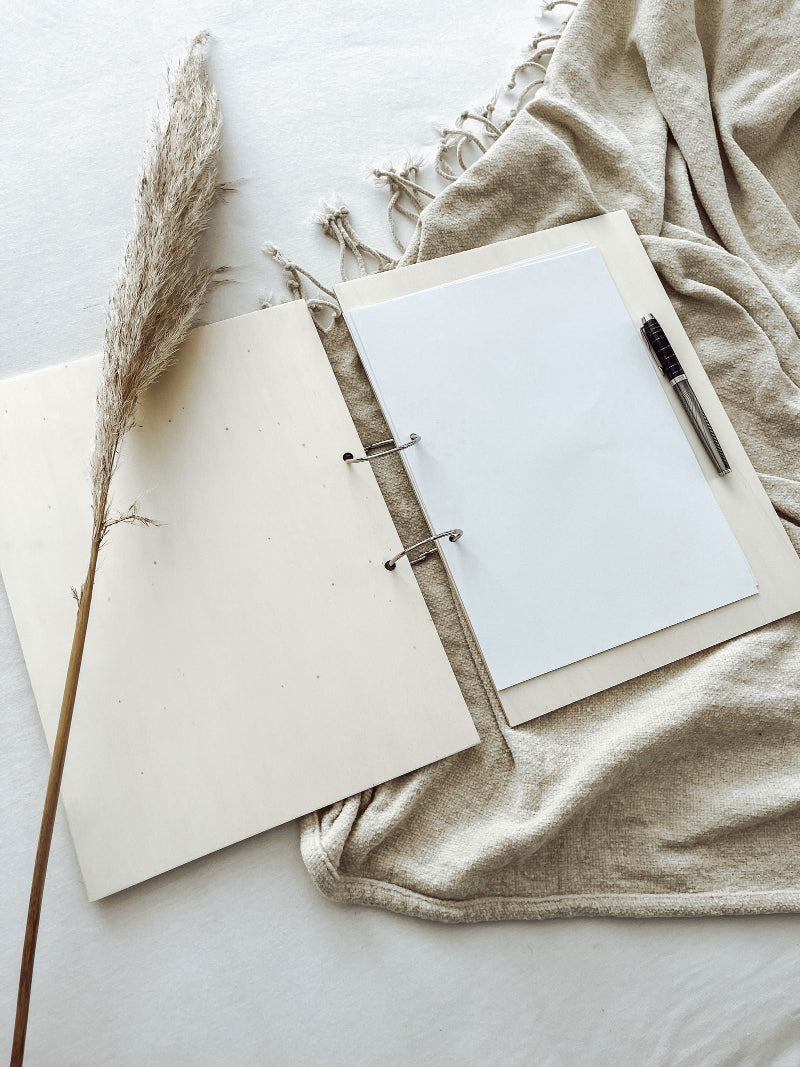 Binnenzijde van houten gastenboek met blanco pagina’s en ringbandbinding