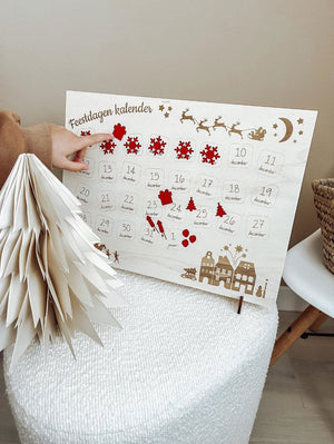 Feestdagen houten aftelkalender - yourlittlefamily-nl - De houten aftelkalender met stickers en een vinger wat wijst naar een sticker. 